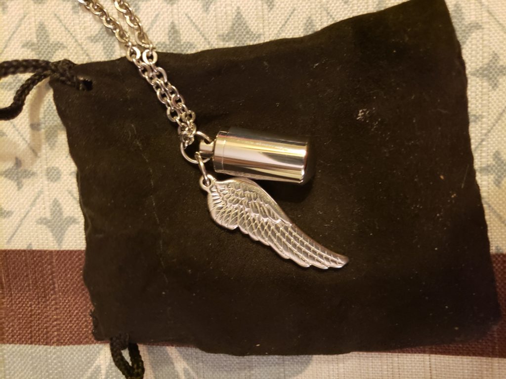 angel wing on a necklace with a small vial