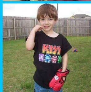 The Kid as a young boy, standing in the backyard wearing a black KISS T-shirt with colorful teddy bear designs and holding a red toy.
