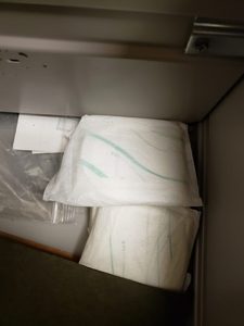Several white sanitary pads, some unwrapped, with pale green markings, discovered inside the drawer of a secondhand metal filing cabinet.